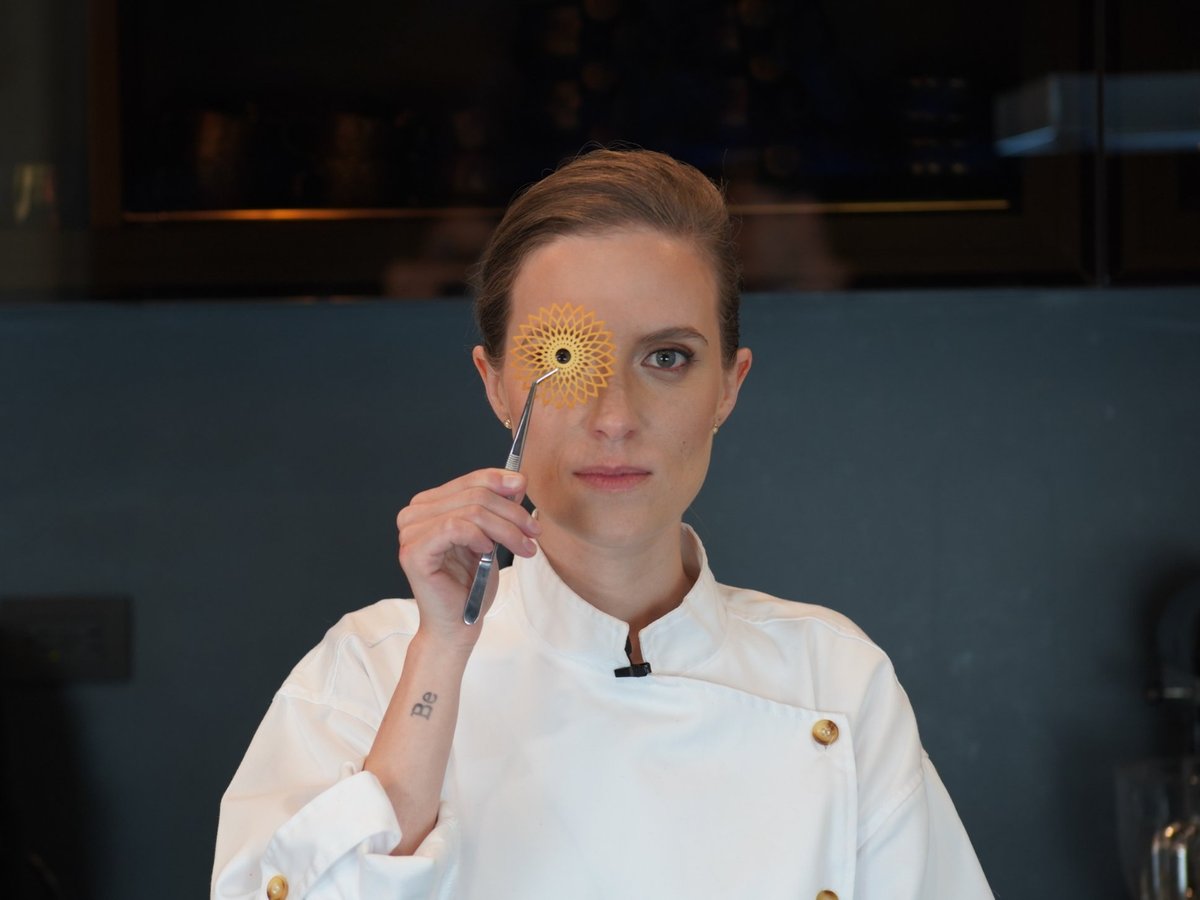 Moni Ríos sostiene con pinzas una teja calada de galleta frente a su ojo