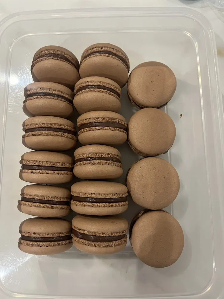 Macarons de cacao rellenos de ganache de chocolate en un recipiente