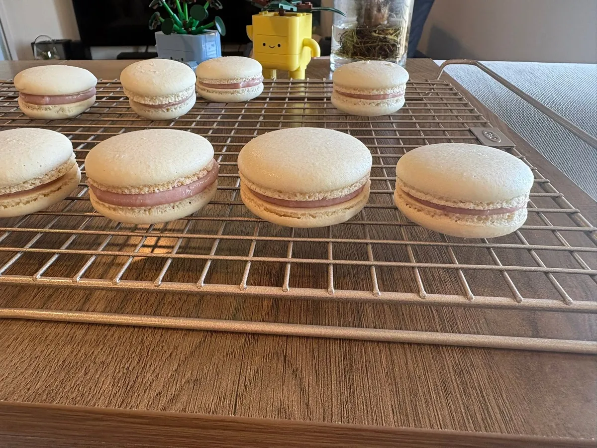 Macarons rellenos de ganache de frambuesa enfriándose sobre una rejilla