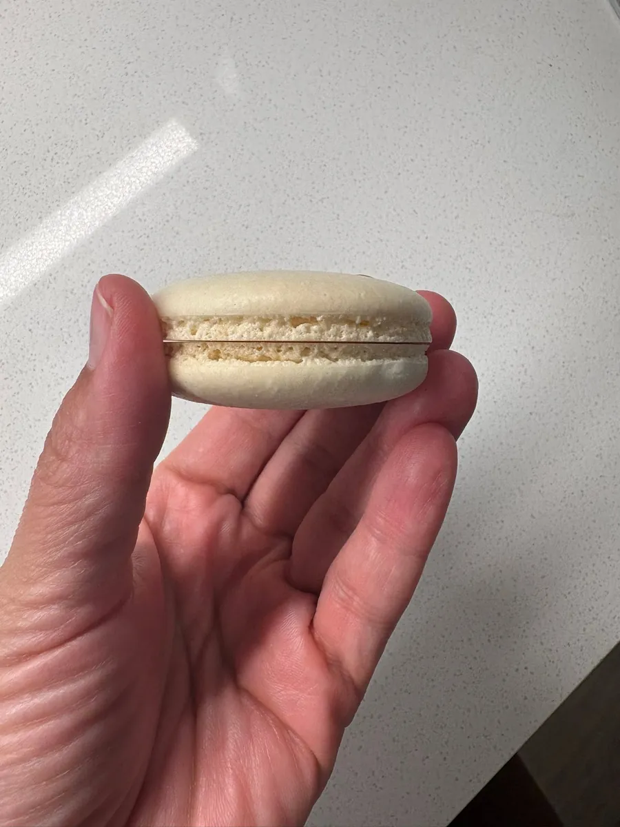 Macaron sostenido en la mano con pie parejo e interior lleno