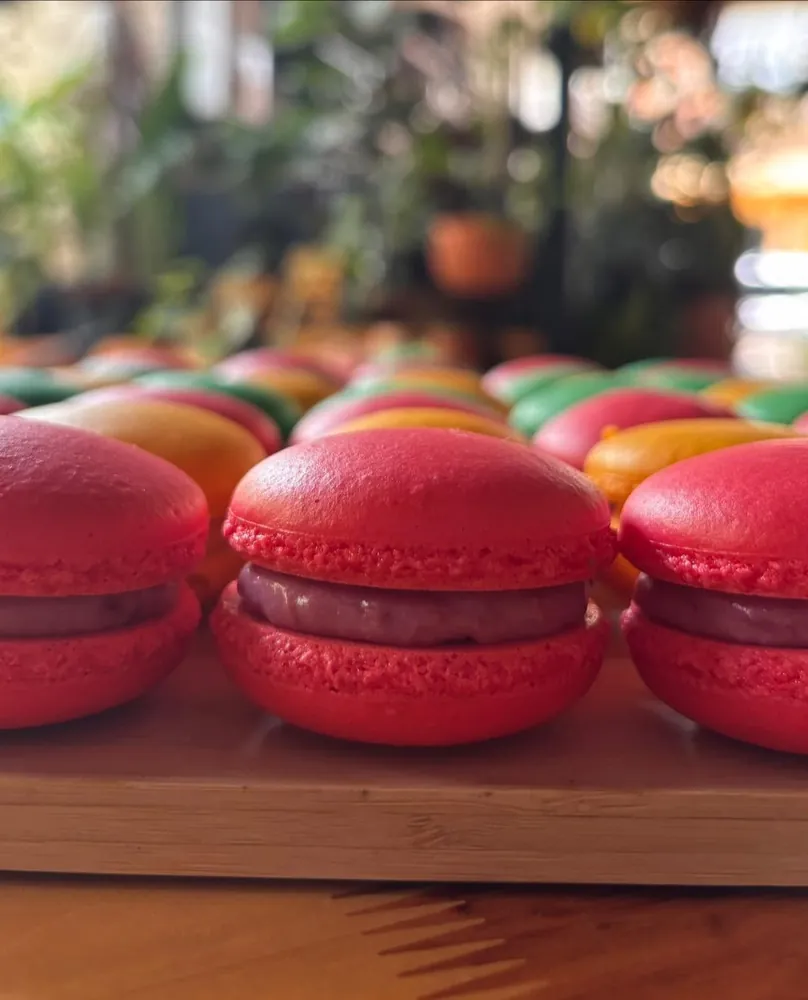 Macarons rojos rellenos de ganache de frambuesa sobre una tabla de madera