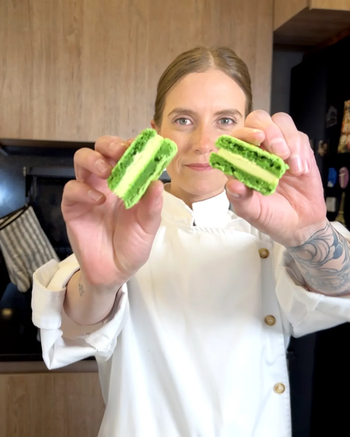 Moni Ríos muestra el interior de un macaron de pistacho partido por la mitad en la cocina de su casa