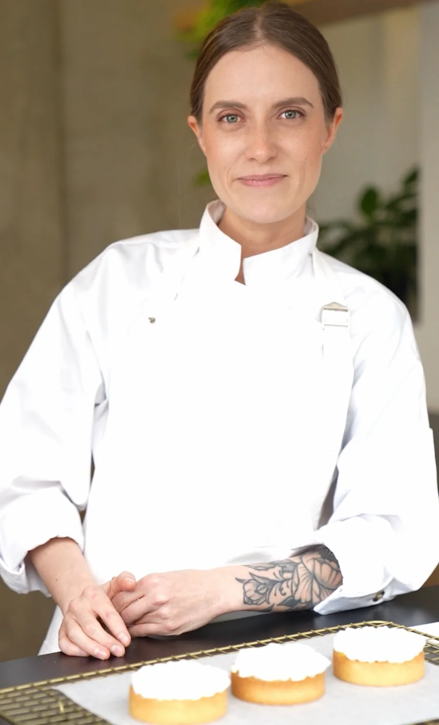 Moni Ríos con chaqueta de chef, junto a tres tartaletas sobre una rejilla