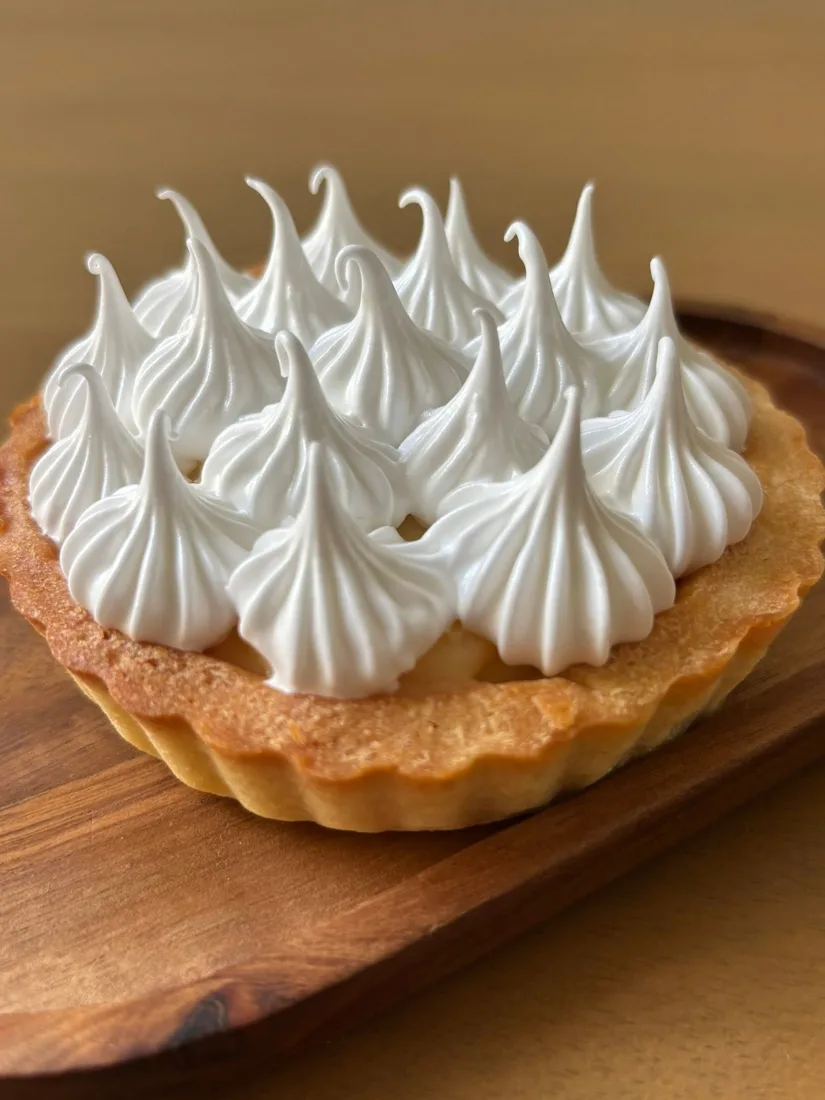 Tarta de limón con merengue en picos sobre una tabla de madera