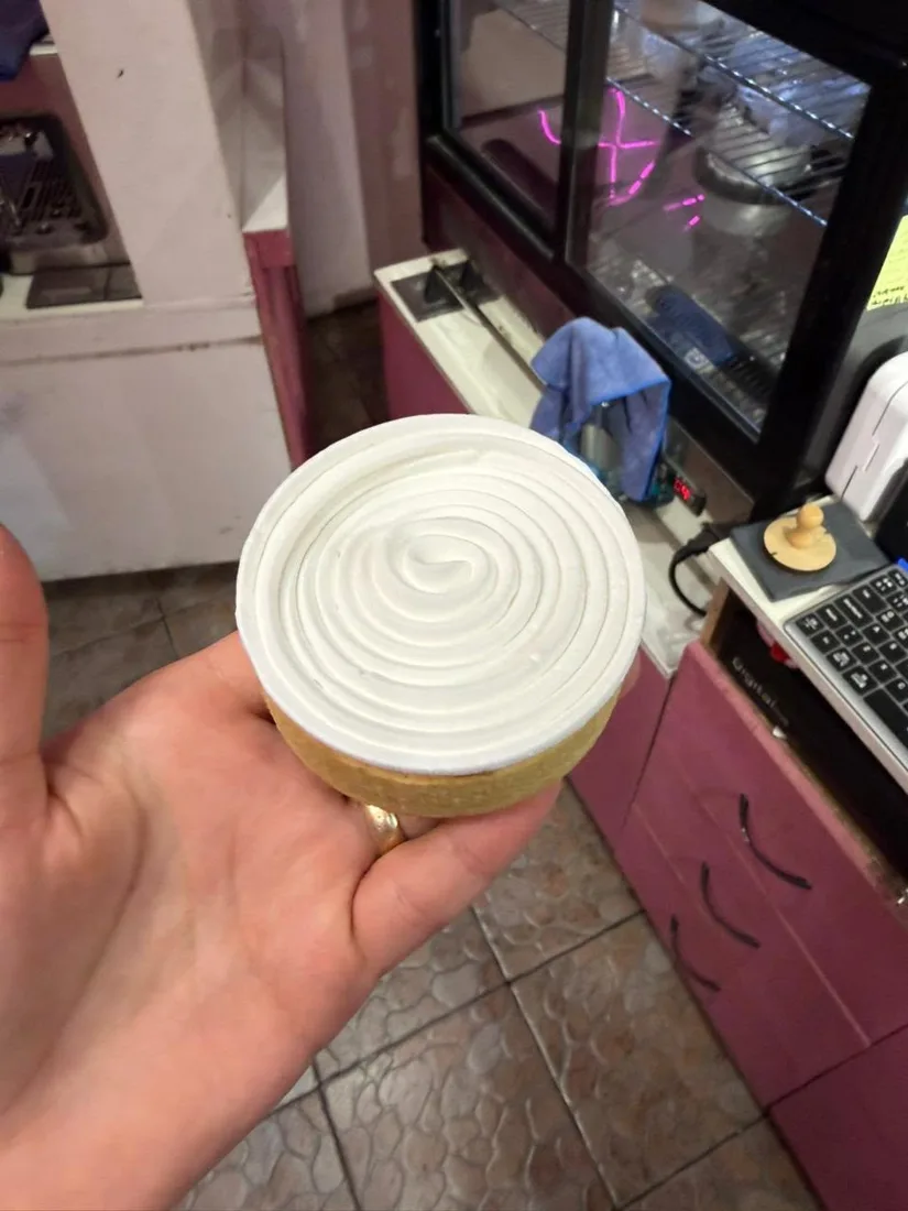 Tartaleta con merengue en espiral sostenida en la mano