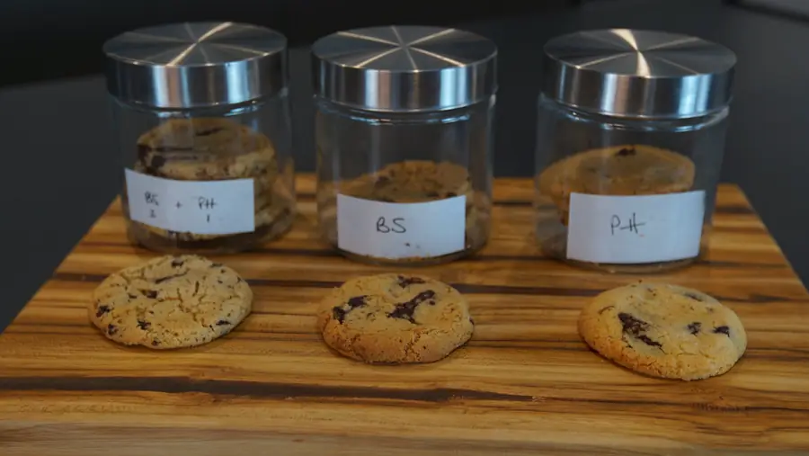 Tres frascos rotulados con tres versiones de la misma cookie y una galleta de cada una delante