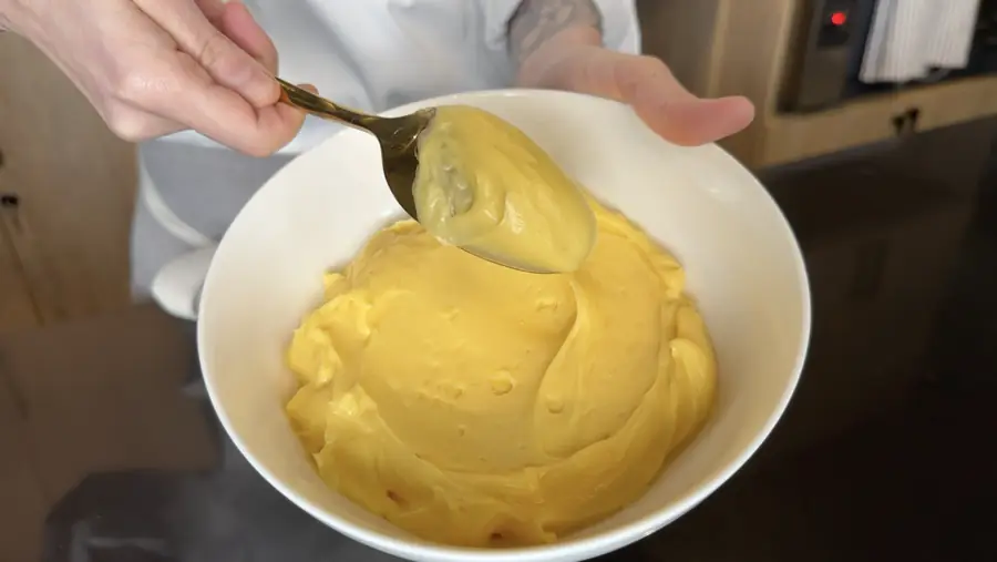 Crema pastelera en un bol, con una cuchara que muestra su textura