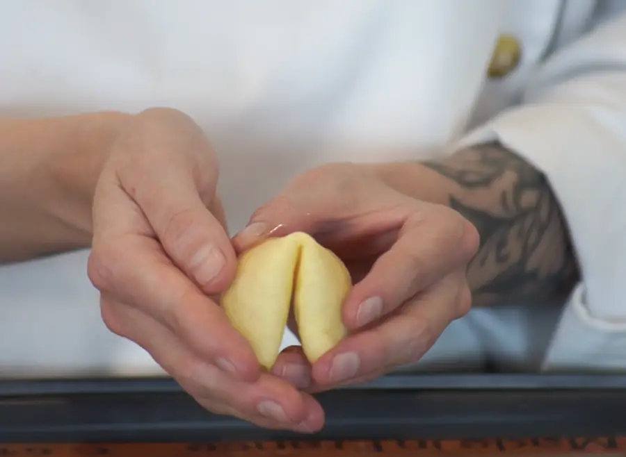 Manos de Moni Ríos dando forma a una galleta de la fortuna