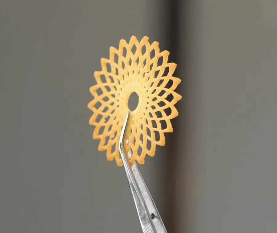 Tuile calada en forma de flor sostenida con pinzas